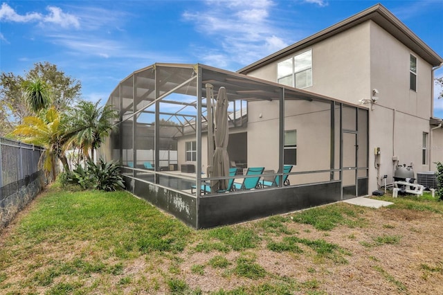 rear view of property with a lanai, central AC, a lawn, and a swimming pool