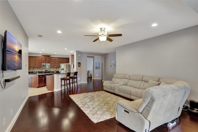 living room featuring ceiling fan and dark hardwood / wood-style floors