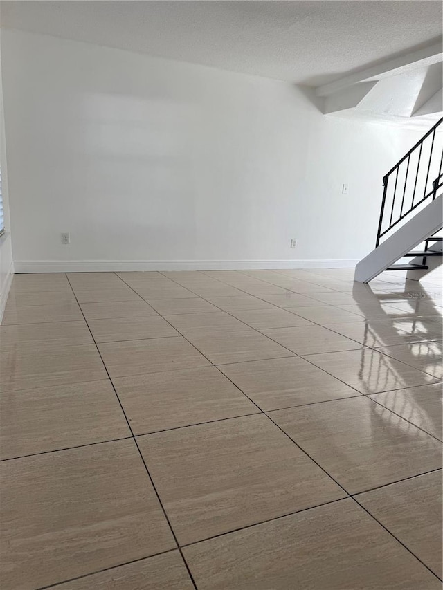 unfurnished room featuring a textured ceiling and light tile patterned floors