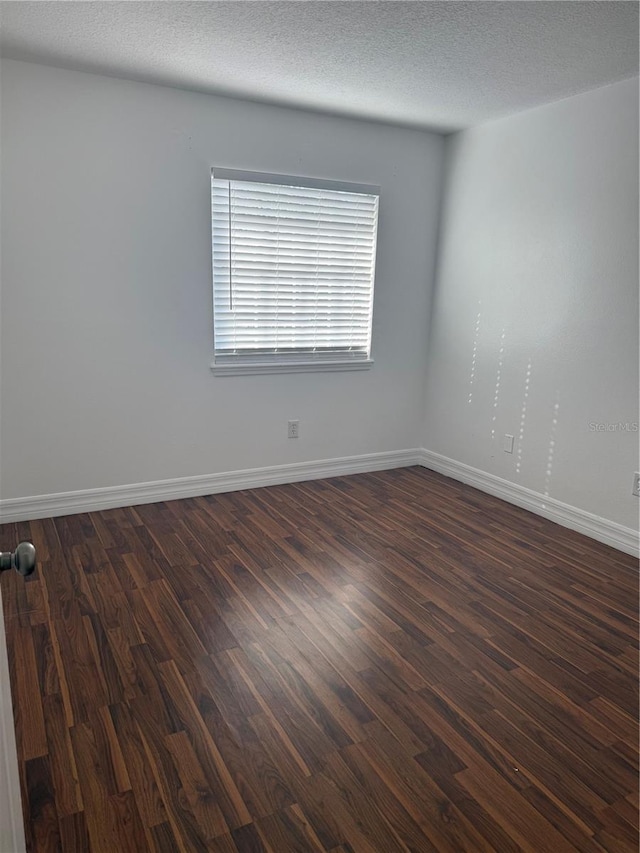 spare room featuring dark hardwood / wood-style flooring and a textured ceiling