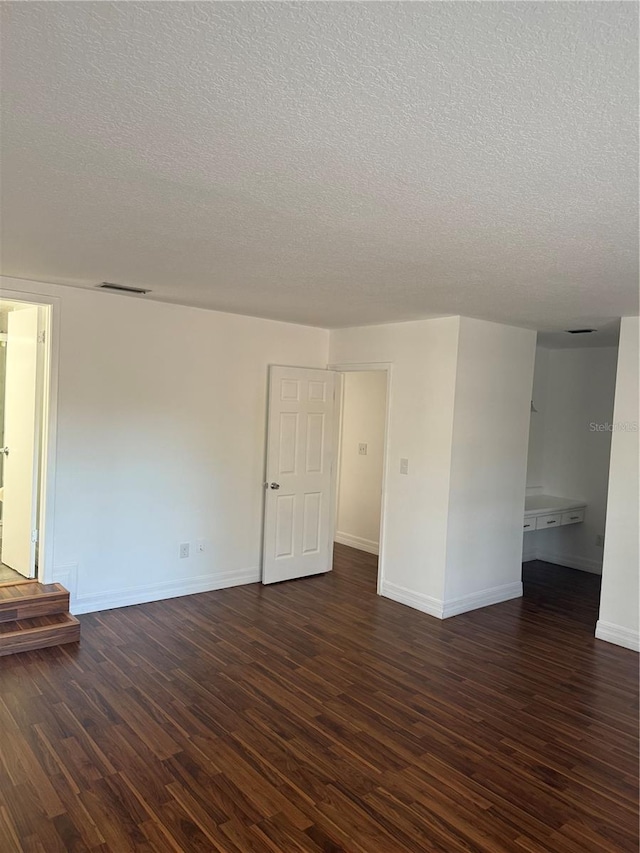 empty room featuring dark hardwood / wood-style flooring and a textured ceiling