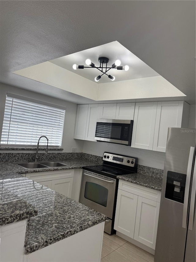 kitchen with white cabinetry, sink, light tile patterned floors, a tray ceiling, and stainless steel appliances