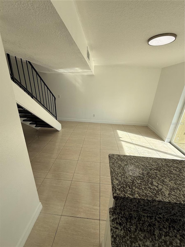 stairway featuring tile patterned flooring and a textured ceiling