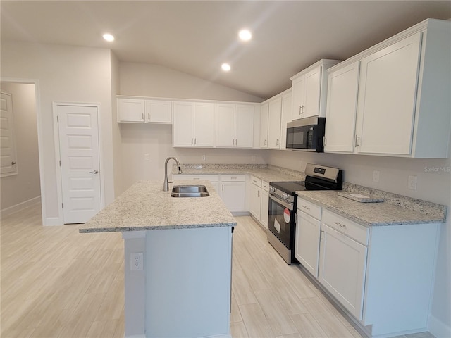 kitchen with light stone counters, electric range, a kitchen island with sink, white cabinets, and sink