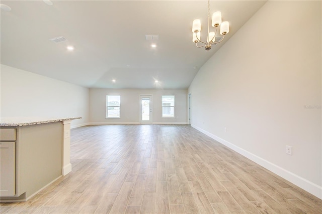 unfurnished living room featuring light hardwood / wood-style floors, an inviting chandelier, and vaulted ceiling