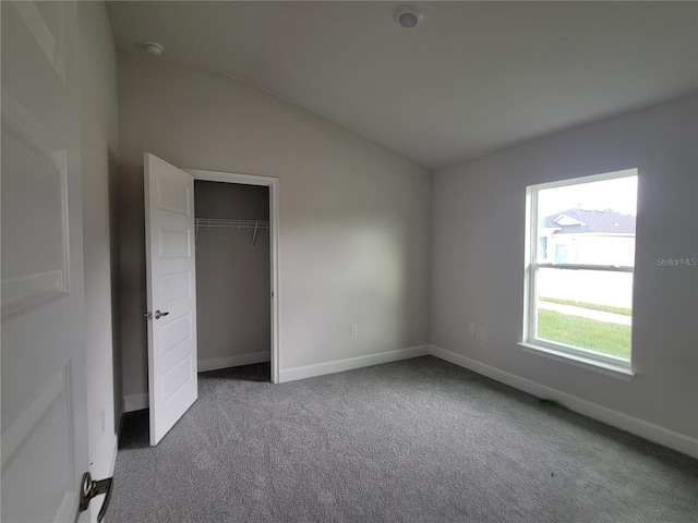 unfurnished bedroom featuring lofted ceiling, a closet, and carpet