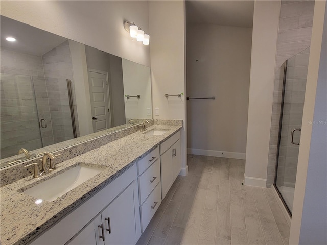 bathroom with hardwood / wood-style flooring, a shower with shower door, and vanity