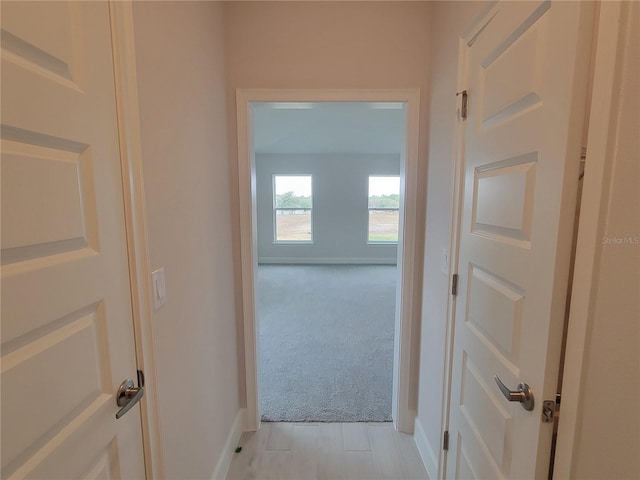 hallway with light carpet and baseboards