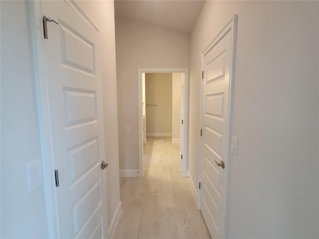 corridor with baseboards and light wood-style flooring