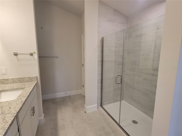 bathroom with a shower stall, baseboards, wood finish floors, vanity, and vaulted ceiling