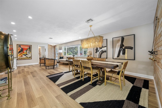 dining room featuring light wood-type flooring and an inviting chandelier