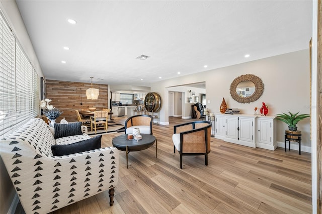 living room with light hardwood / wood-style flooring and wooden walls