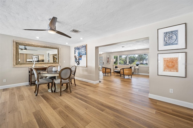 dining area with a textured ceiling, ceiling fan, and light hardwood / wood-style floors