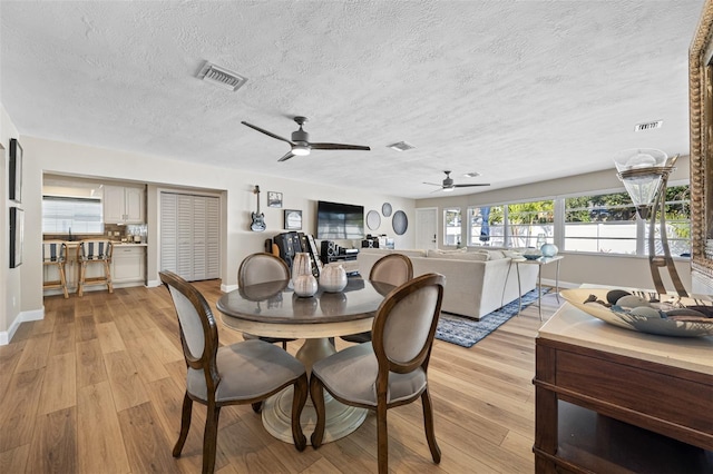 dining space featuring ceiling fan, a textured ceiling, and light hardwood / wood-style flooring