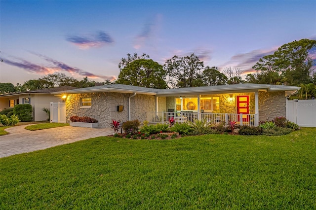 back house at dusk with a porch and a yard