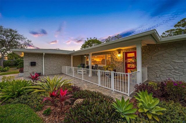 back house at dusk featuring a porch