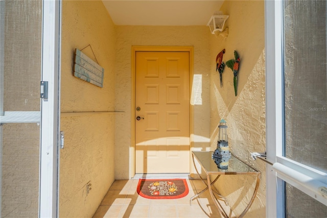 doorway to outside with a textured wall and tile patterned flooring