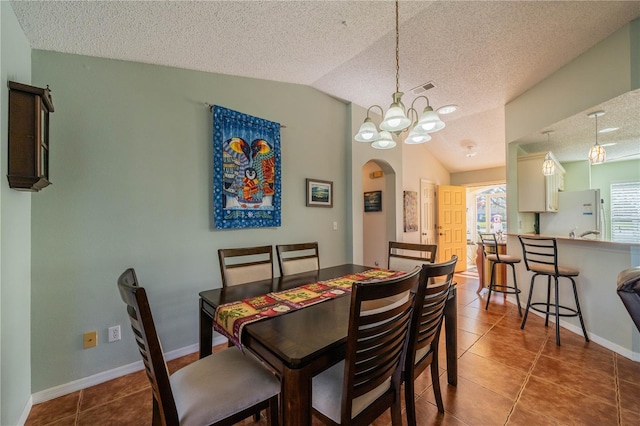 tiled dining area featuring arched walkways, visible vents, vaulted ceiling, and a textured ceiling