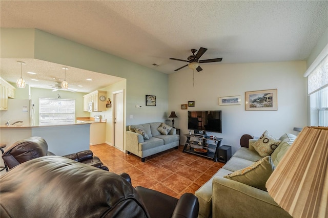 living area featuring a healthy amount of sunlight, ceiling fan, dark tile patterned floors, and vaulted ceiling