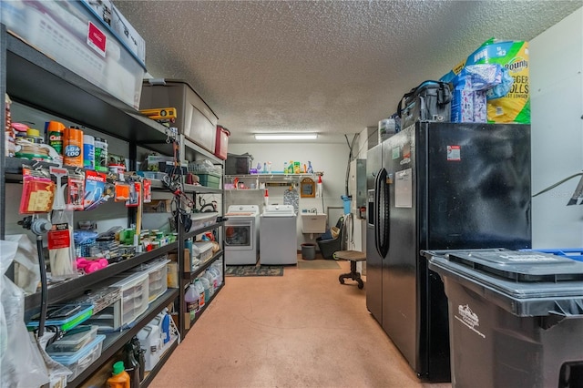 kitchen with washing machine and clothes dryer, a sink, a textured ceiling, concrete floors, and black fridge