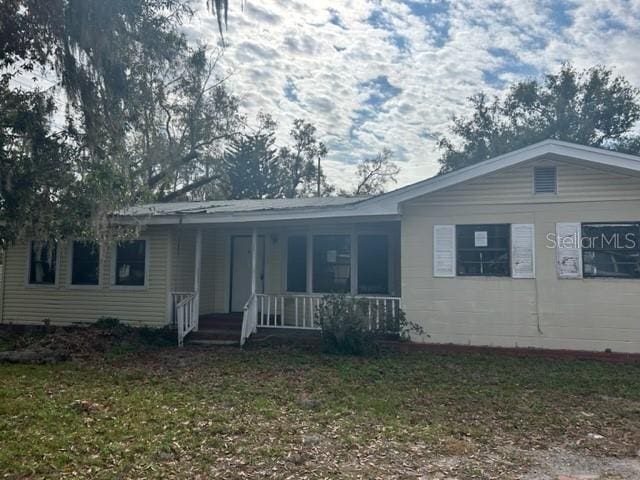 ranch-style house with a front yard and a porch