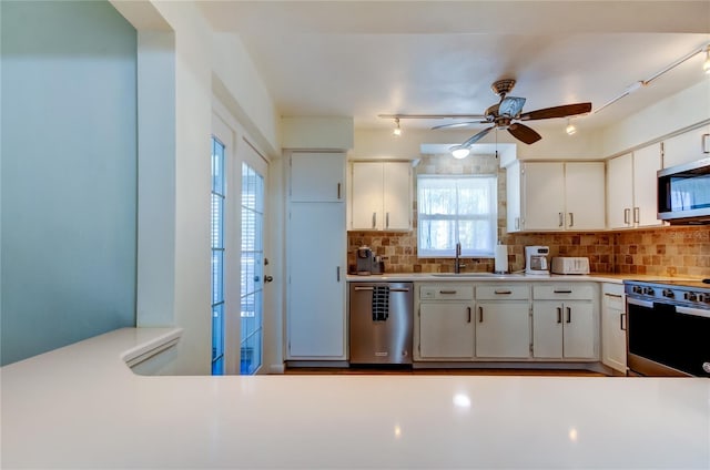 kitchen with decorative backsplash, white cabinetry, ceiling fan, and stainless steel appliances