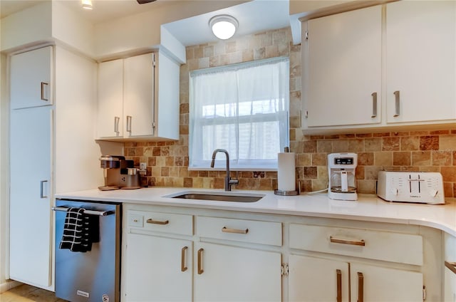 kitchen featuring stainless steel dishwasher, white cabinets, sink, and tasteful backsplash