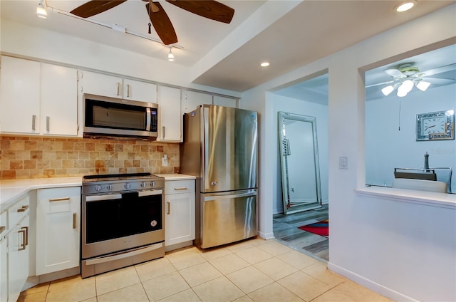 kitchen with white cabinets, light tile patterned floors, backsplash, and stainless steel appliances