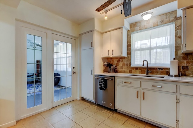 kitchen with decorative backsplash, stainless steel dishwasher, sink, light tile patterned floors, and white cabinets