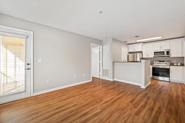 kitchen with white cabinetry, hardwood / wood-style floors, a textured ceiling, and appliances with stainless steel finishes