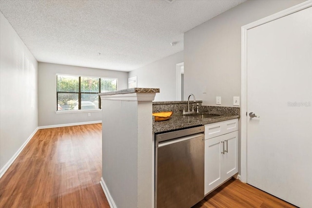 kitchen featuring sink, white cabinetry, dark stone countertops, kitchen peninsula, and stainless steel dishwasher