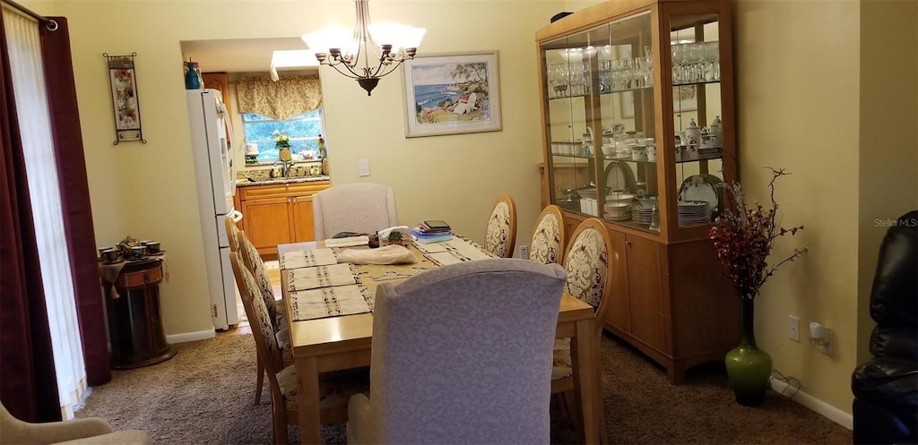 dining room featuring an inviting chandelier, dark carpet, and sink