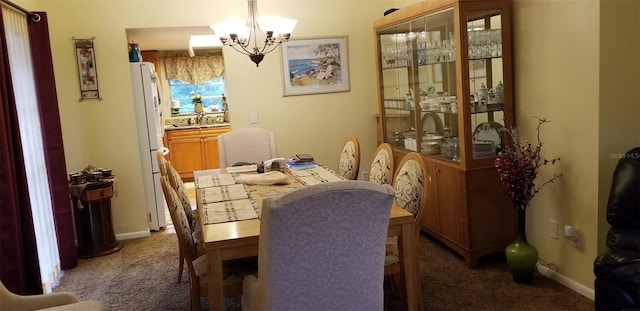 dining room featuring an inviting chandelier, dark carpet, and sink