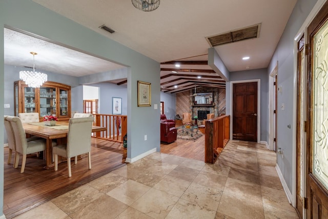 entryway with a fireplace, lofted ceiling with beams, and a notable chandelier