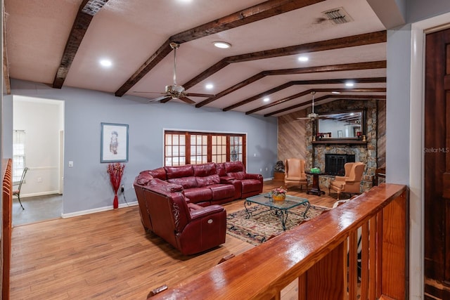 living room featuring a fireplace, light wood-type flooring, vaulted ceiling with beams, and ceiling fan