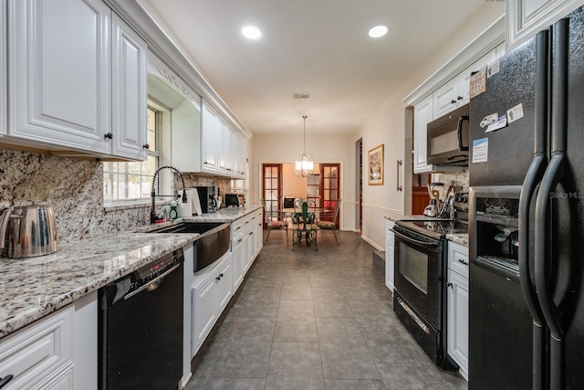 kitchen featuring black appliances, decorative light fixtures, white cabinetry, sink, and backsplash