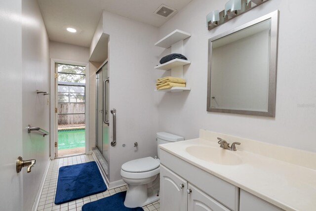 bathroom with vanity, toilet, tile patterned floors, and a shower with door