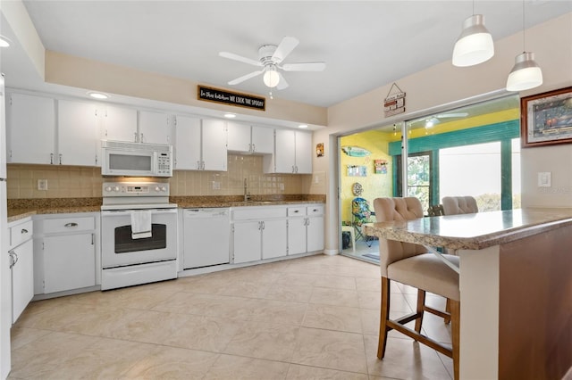 kitchen with a kitchen breakfast bar, white cabinets, decorative light fixtures, and white appliances