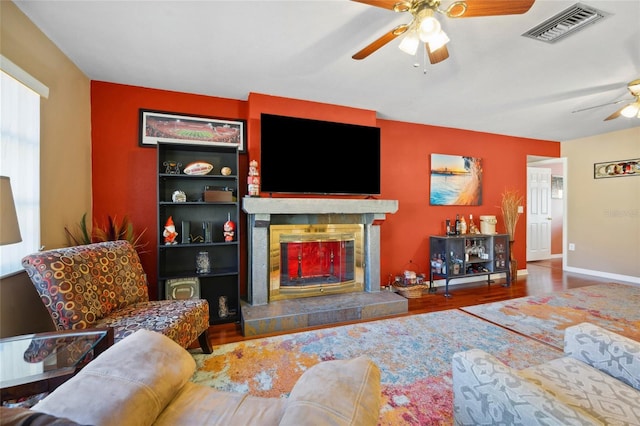 living room with hardwood / wood-style flooring, built in features, and ceiling fan