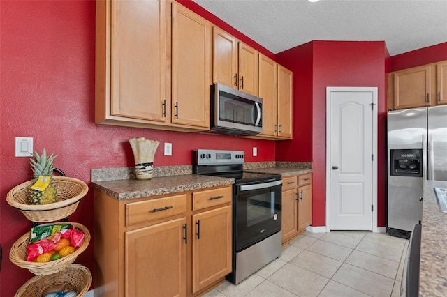 kitchen featuring appliances with stainless steel finishes, a textured ceiling, and light tile patterned floors