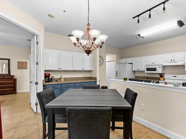 tiled dining room with a chandelier and track lighting