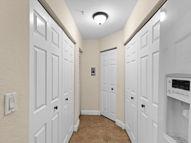 hallway with light tile patterned flooring and a textured ceiling