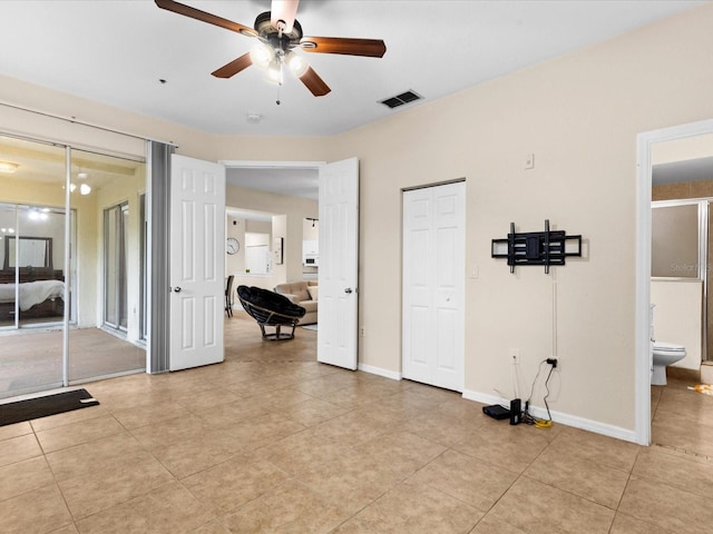 interior space with light tile patterned floors, ensuite bath, and ceiling fan