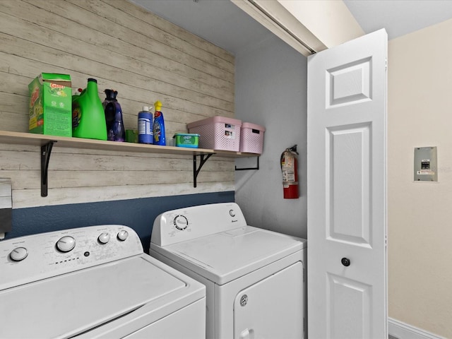 clothes washing area featuring separate washer and dryer and wood walls