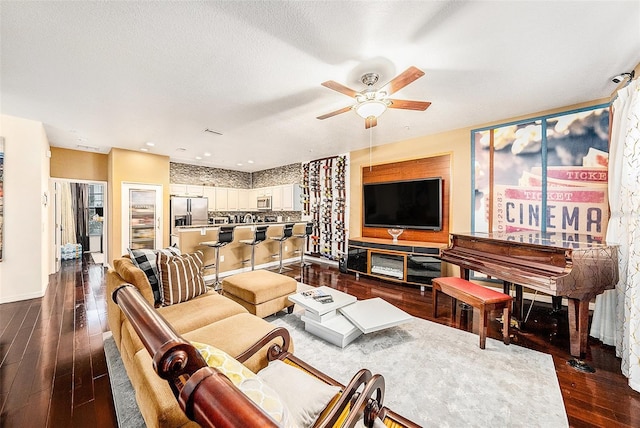 living room featuring a textured ceiling, dark wood-type flooring, and ceiling fan