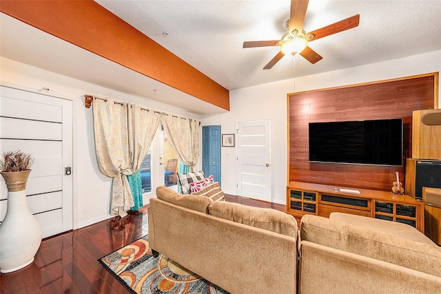 living room featuring ceiling fan, dark wood-type flooring, and a textured ceiling