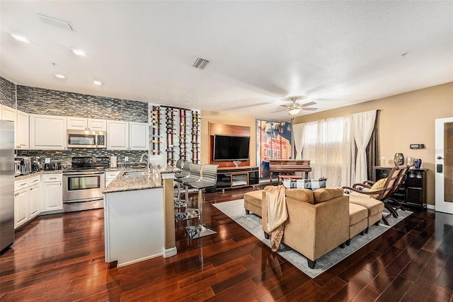 living room featuring ceiling fan, dark hardwood / wood-style floors, and sink