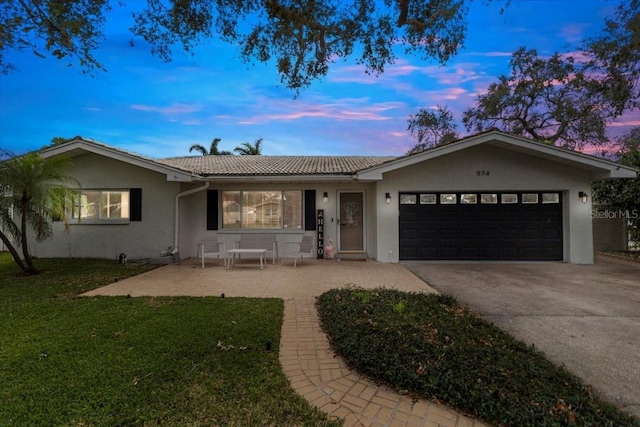 ranch-style house with a garage and a lawn