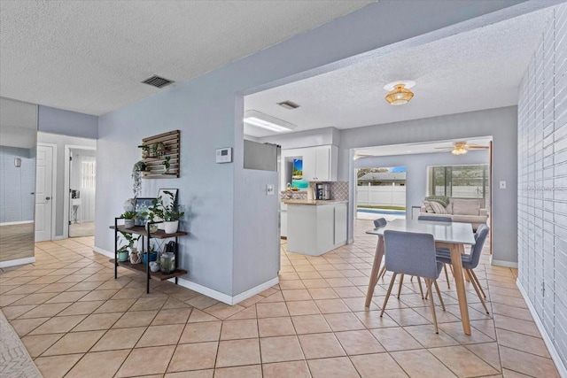 kitchen with ceiling fan, white cabinets, light tile patterned flooring, and a textured ceiling