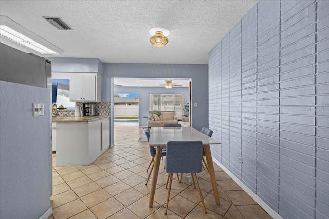 dining space featuring ceiling fan, light tile patterned floors, and a textured ceiling